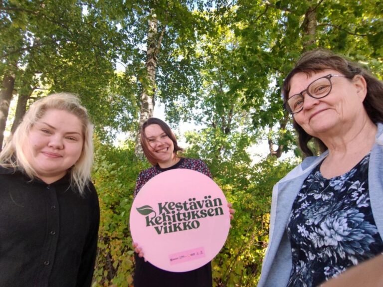 Kolme ihmistä kuvattavana. Kyltissä lukee "Kestävän kehityksen viikko".